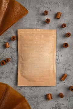 Natural fruit leather rolls and sheets arranged around craft paper ziplock pouch mock up on grey concrete background