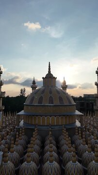 Beautiful aerial view of 201 Dome Mosque in Tangail during a golden sunset with a dramatic sky.