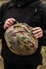 Obraz premium Woman holding military camouflage helmet in tactical vest