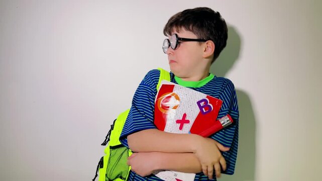A young schoolboy looks around with an anxious and fearful expression, tightly clutching his notebook and school supplies. Wearing a bright green backpack and striped shirt, he appears nervous and int