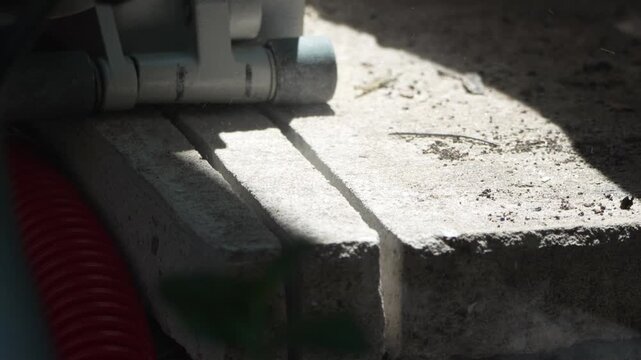 Precision masonry saw cutting grooves into heavy concrete slab outdoors on building site. Macro close-up shot.