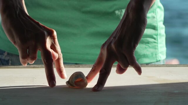 Playful finger walking game with seashell on wooden coastal table in static medium shot