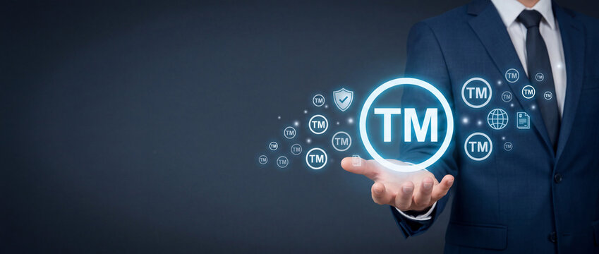 Businessman Holding Glowing Trademark TM Symbol Representing Intellectual Property Rights, Brand Protection, Copyright Law, and Corporate Identity Registration Concept on Dark Background