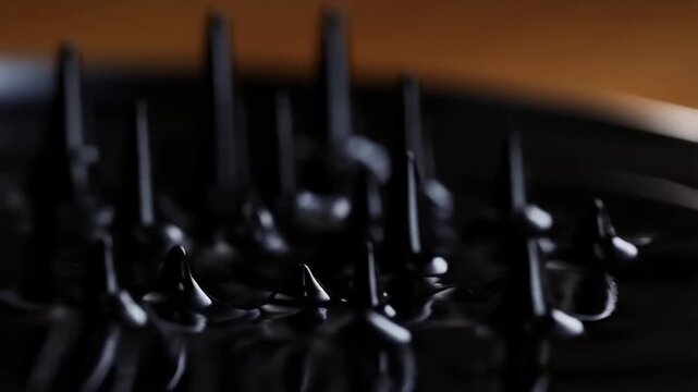 Black ferrofluid rising into sharp spikes under a magnet, macro