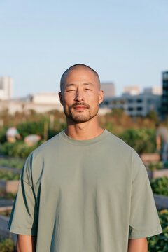 Portrait of a shaved head man wearing a green shirt in a community garden for wellness profile and lifestyle banner design