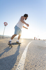 Skater rides along a coastal path during sunset with bright sky and sun setting in the background © KONSTANTIN SHISHKIN
