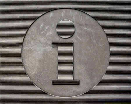 Close up of a metallic information symbol on a textured gray wall, public information sign background