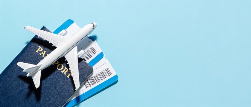 White toy airplane resting on passport and boarding pass against blue background