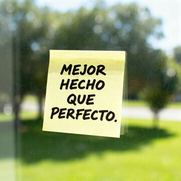 Yellow sticky note with 'Mejor Hecho Que Perfecto' message on glass