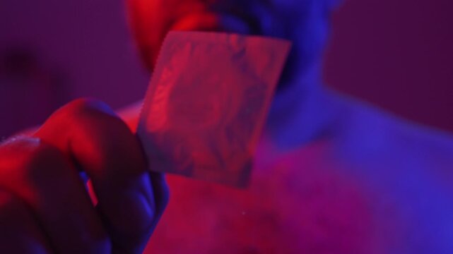 Protection, safe love and contraceptive concept. Bearded man showing latex condom package to camera