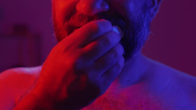 Protection, safe love and contraceptive concept. Bearded man opening latex condom his tooth