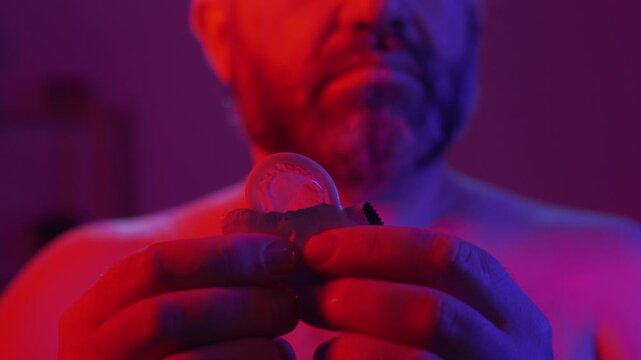 Protection, safe love and contraceptive concept. Bearded man take out latex condom from package