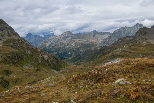 Dramatic rocky mountain valley with alpine meadows and low clouds in the Swiss Alps near Joriseen.