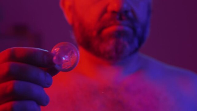 Protection, safe love and contraceptive concept. Bearded man showing latex condom to camera