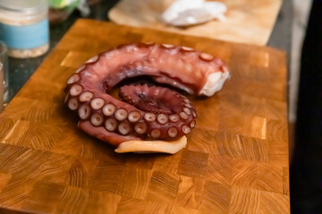 Boiled octopus tentacle on wooden cutting board © Olesia Basova