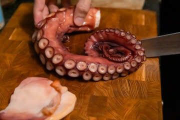 Boiled octopus tentacle with knife on cutting board © Olesia Basova