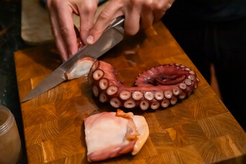 Sliced boiled octopus tentacle pieces on wooden board © Olesia Basova