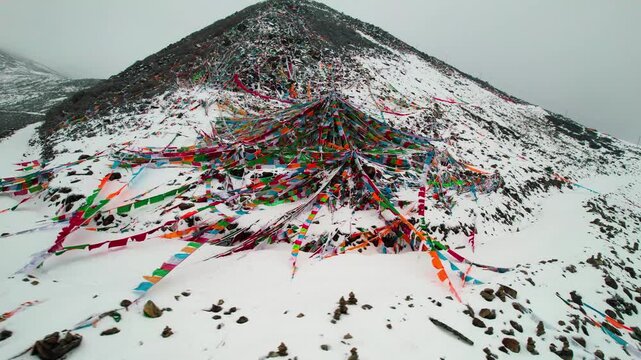 Colorful prayer flags spread over a snowy Sejila Mountain slope