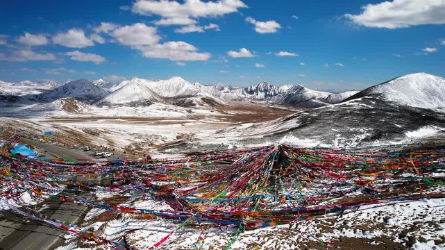 Colorful prayer flags against a snowy Tibetan plateau panorama