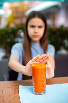 Teenager pushing away glass of fresh vegetable smoothie showing rejection and stop gesture