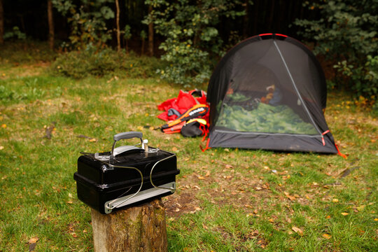 Portable charcoal grill on wooden stump with camping mesh tent at forest campsite background cookout barbecue equipment picnic lawn wilderness setup nature travel adventure gear backyard leisure lifes