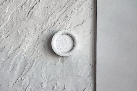 Textured grey concrete and decorative plaster wall background with minimal round wall sconce lamp