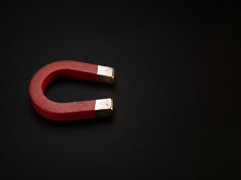 Red horseshoe magnet on a dark black background illustration