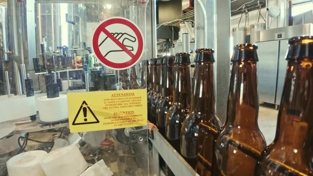 Brown glass bottles moving along a conveyor belt on an automated bottling line at a brewery or factory.