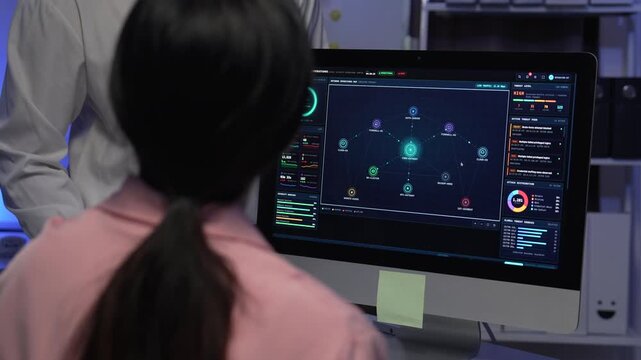 Programmers analyzing network security data on desktop monitor in dark office