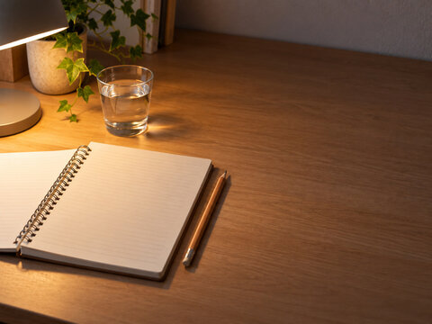 夜のデスクに開いた排尿日誌用のノートと鉛筆