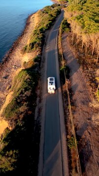 A bcamper van journey along the coastal roads of Cagliari, Sardinia, showcasing scenic views of the coastline, vibrant trees, and the serene blue waters. Perfect for holiday inspiration.
