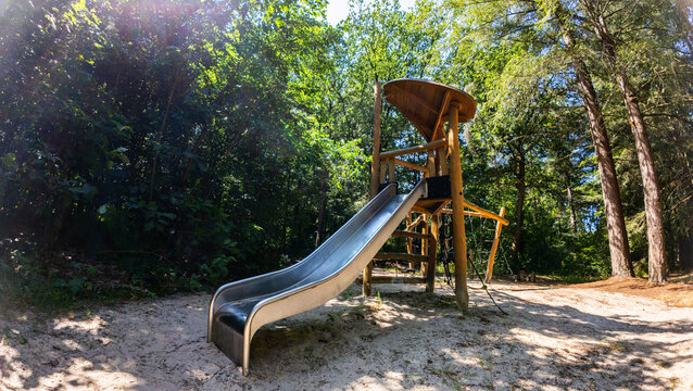 A wooden playground structure with a slide located in a forest park or recreational area in Norg, Netherlands.