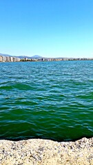 Fototapeta premium Ocean waves in front of a city skyline and blue sky