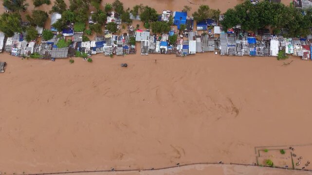 Aerial view of a vulnerable squatter settlement built along a wide, muddy riverbank exposed to severe flood risks in Kathmandu.