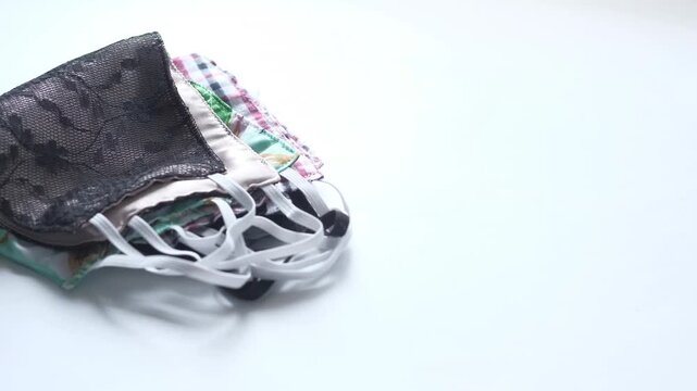 Stack of reusable cloth face masks on white background with lace design and adjustable ear loops