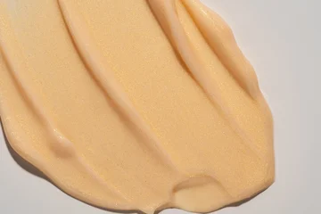 Gold shimmer body cream swatch texture on white. Shiny beige liquid lotion smudge, glittering skincare moisturizer or gel highlighter sample © IKvyatkovskaya