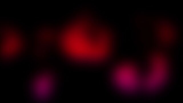 Blurred red and pink light spots glowing on black background. Abstract bokeh lights moving in darkness. Neon glow effect for backdrop overlay