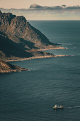 High angle view of vessel navigating along rugged rocky ocean coast under cloudy sky in scandinavia with copy space © Quality by Simon