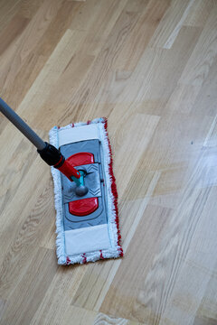 Flat microfiber mop cleaning light wooden parquet floor close up