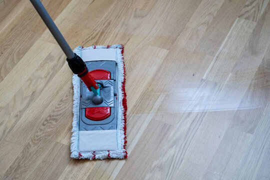 Flat microfiber mop cleaning light wooden parquet floor close up