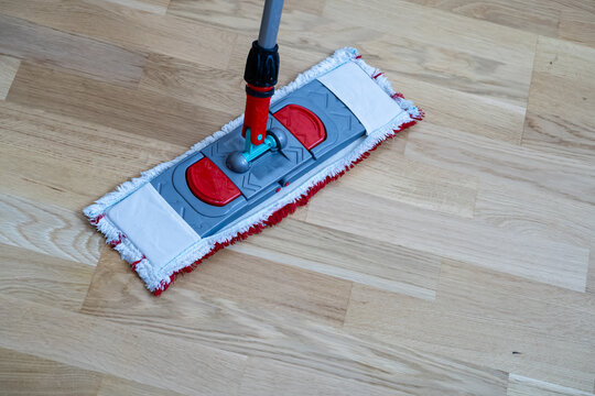 Flat microfiber mop cleaning light wooden parquet floor close up