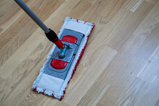 Flat microfiber mop cleaning light wooden parquet floor close up