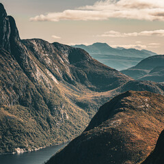 High angle vertical view of layers of mountain ranges and fjord in warm sunlight under cloudy sky in scandinavia with copy space © Quality by Simon
