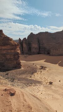 Sun shines to rocky desert landscape near Al Ula, view around from higher sandstone formation viewpoint near Vessel Hole Rock, vertical video