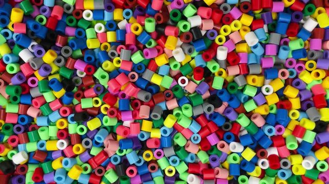 colorful plastic beads scattered in tray bright cylindrical fuse beads, closeup