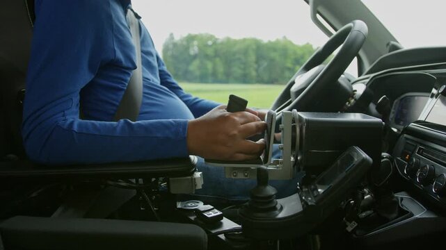 Driver with disability using adaptive driving controls inside a wheelchair accessible vehicle for independent driving. Assistive technology.