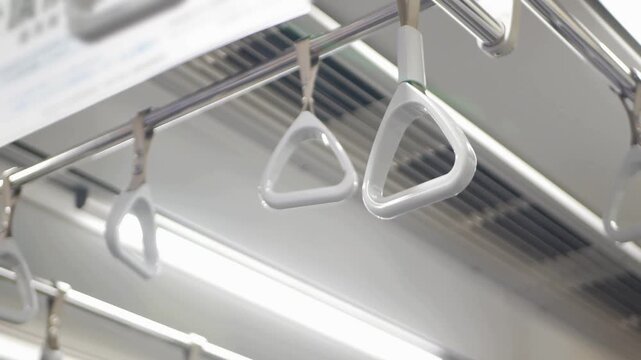 Close up of white plastic hanging passenger handles inside a modern subway train car.