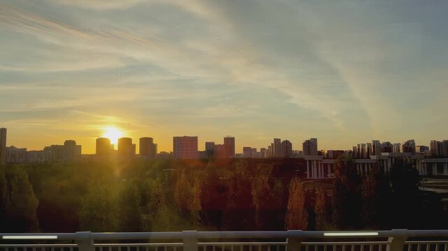 1. Traveling aboard Astana LRT at sunset, with modern residential buildings, landscaped streets, elevated track and glowing evening sunlight, Kazakhstan, shot handheld, 4k footage