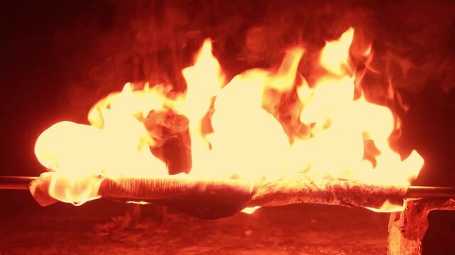 Intense orange flames engulf a long metal bar in this dramatic motion video showing powerful thermal energy and combustion.