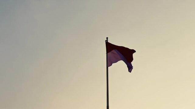 Indonesian red and white national flag waving on tall pole